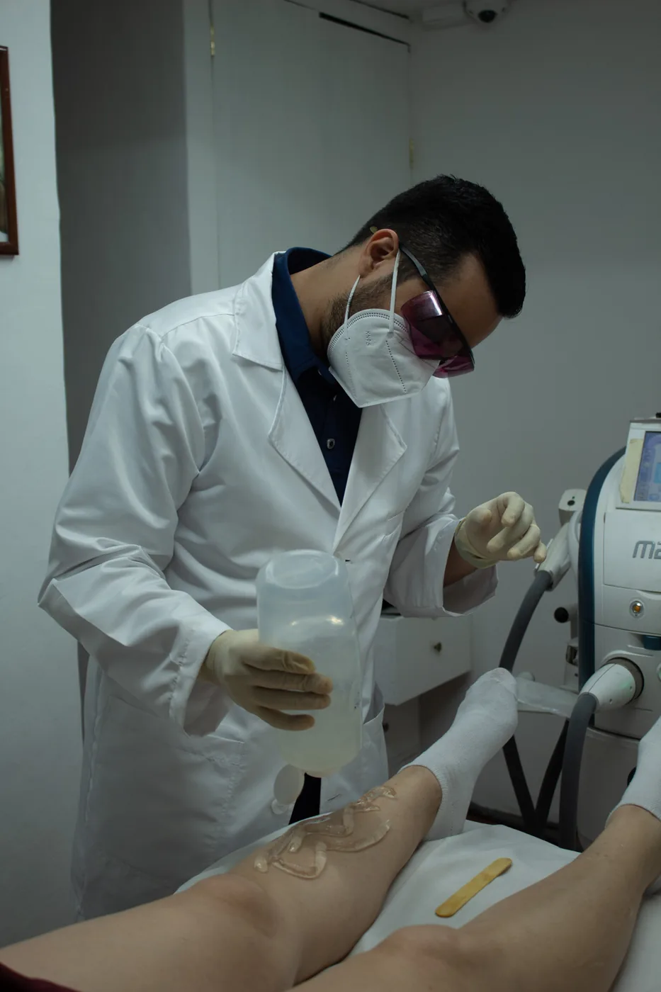 Médico prepara el área antes de aplicar depilación láser, con gafas de protección